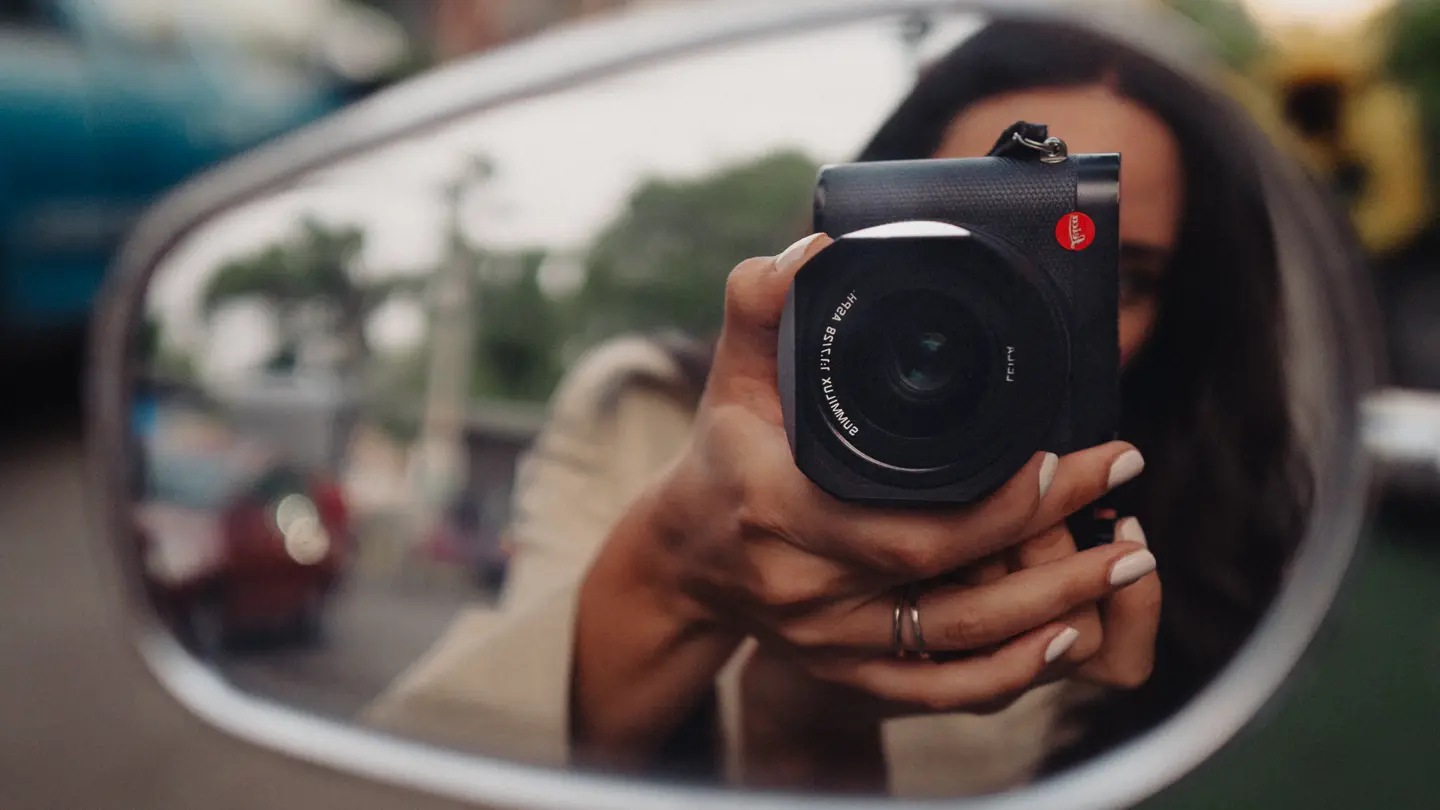 Woman taking a picture with the Leica Q into a side mirror