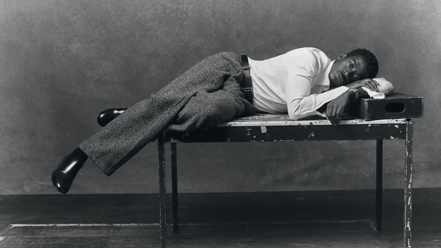 Portrait en noir et blanc de l'acteur Damson Idris allongé sur une table