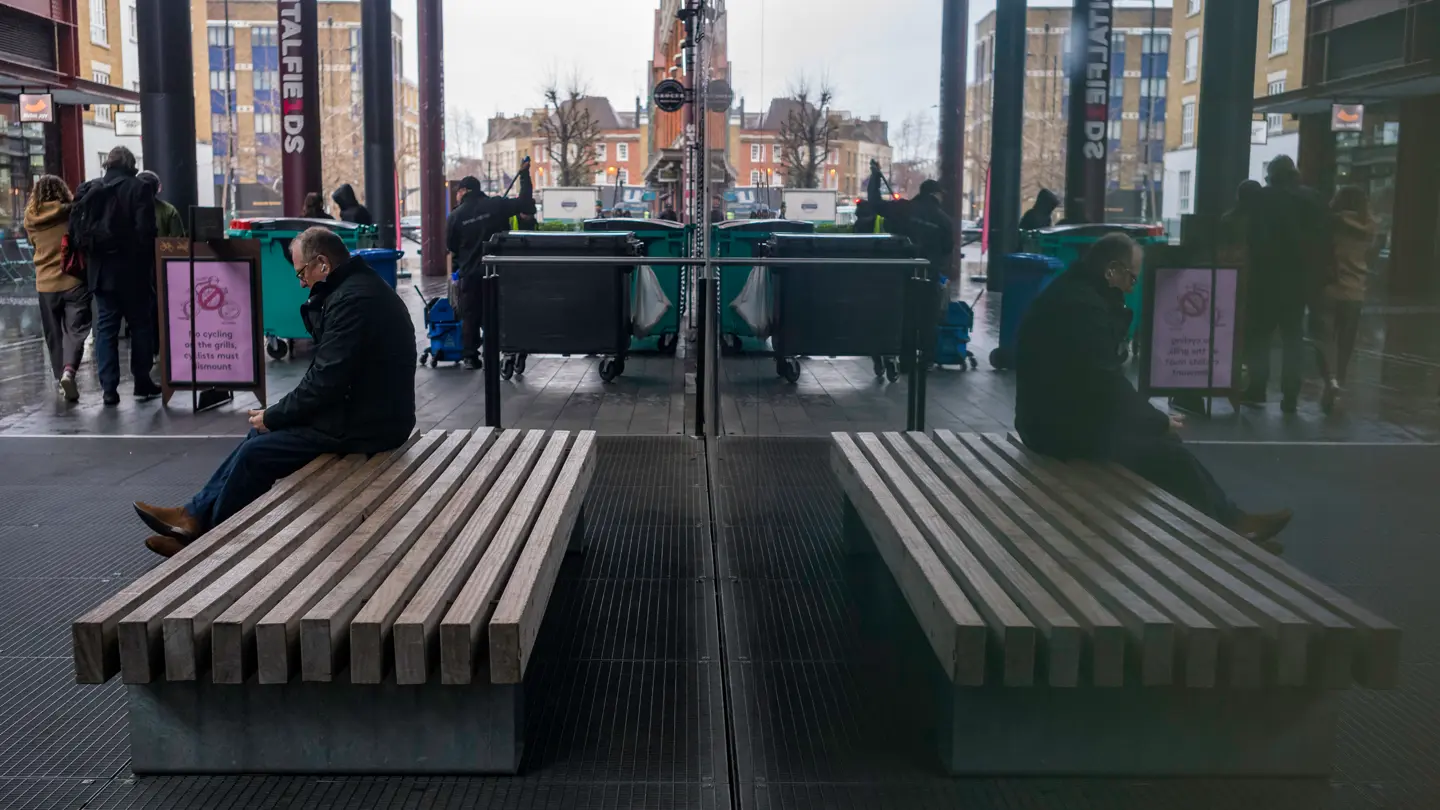 Colour image of a man sitting on a bench