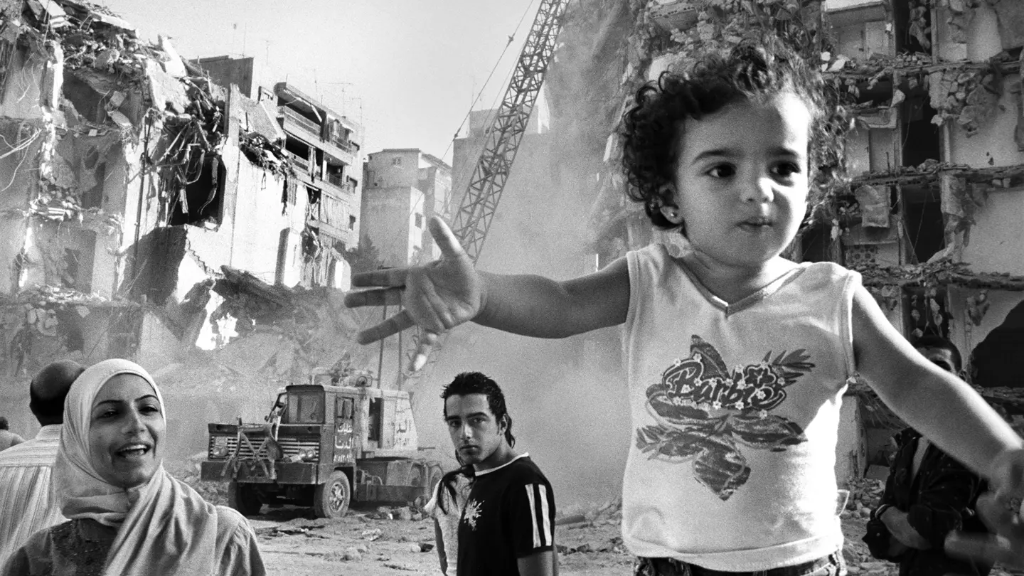 A little girl in a Barbie T-shirt against a backdrop of a war-torn landscape