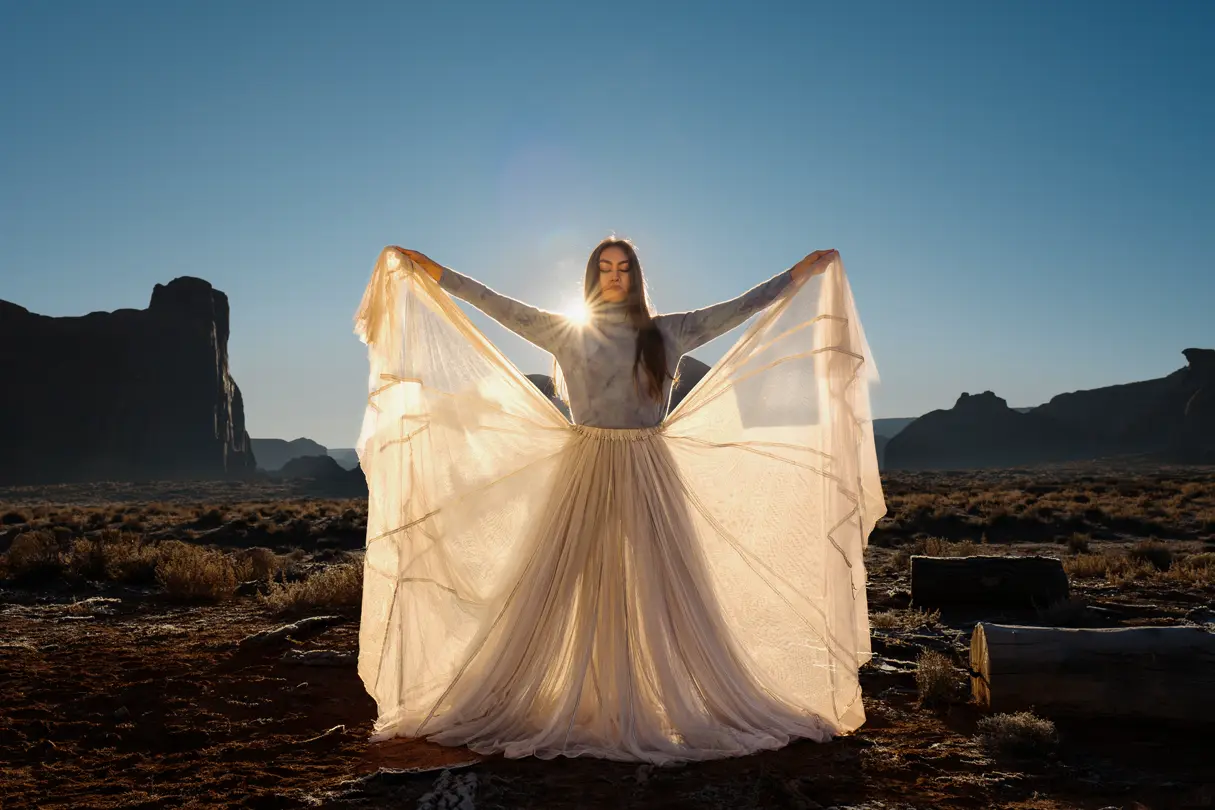 Model in a white dress posing in the desert under the sun