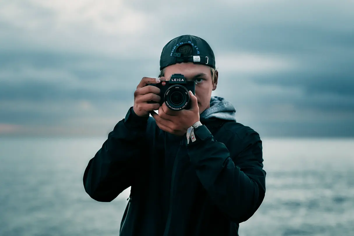 Young man photographing by the sea with the Leica SL3 with the APO-Summicron-SL 21
