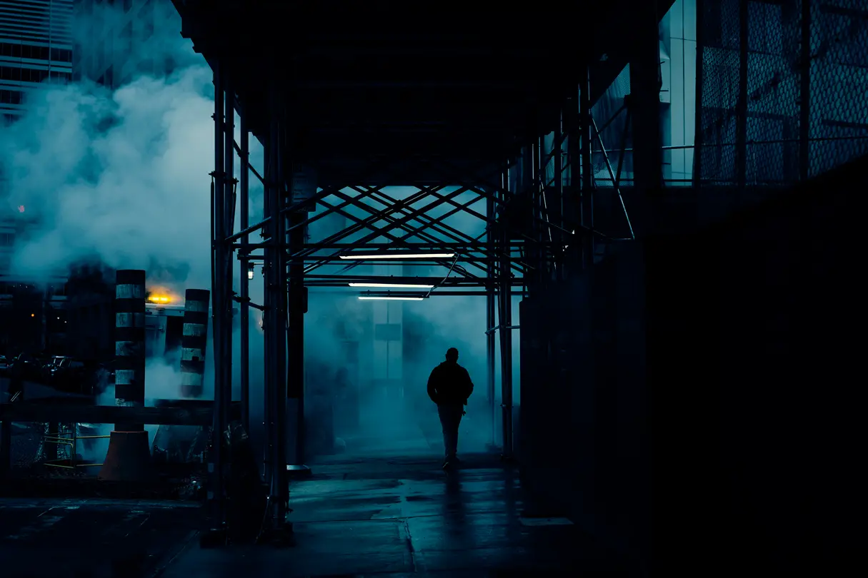A man on a city pavement between construction works