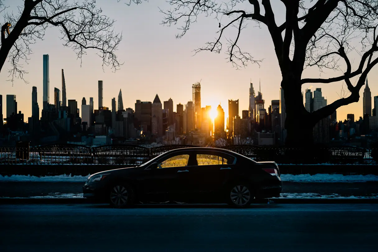 A car parked at the side of the road against a skyline at sunset