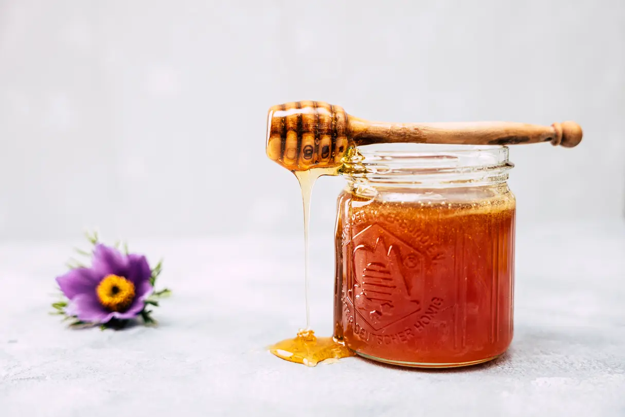 A honey spoon on a jar of honey