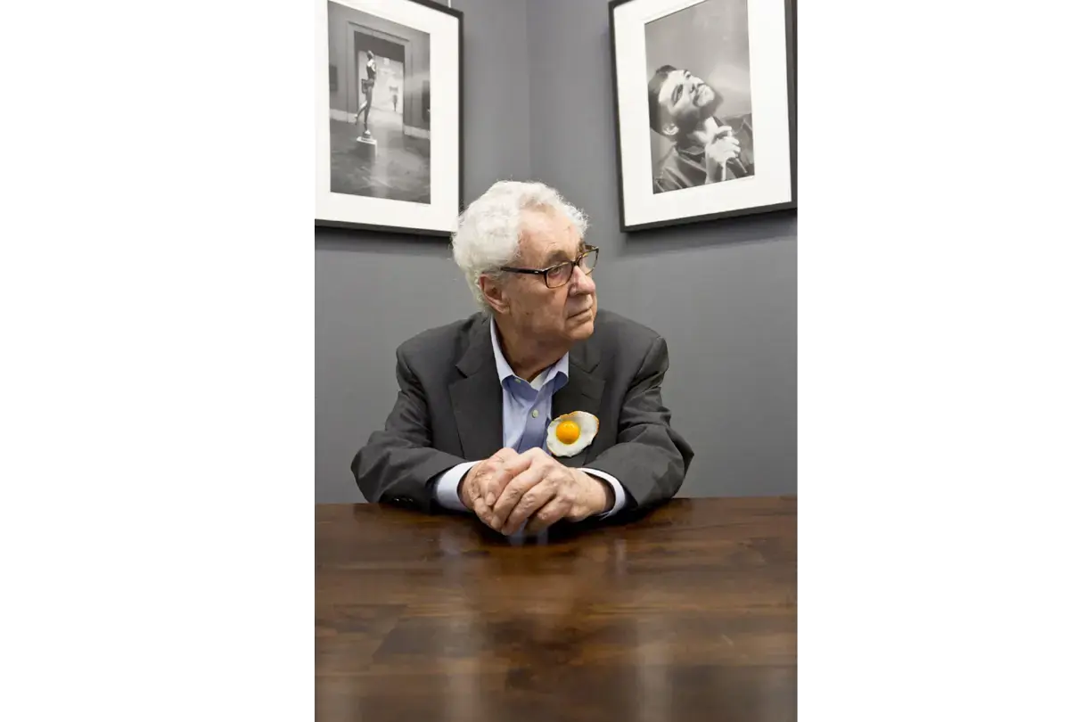 Photographer Elliott Erwitt sitting on a table at a Leica exhibition in Frankfurt