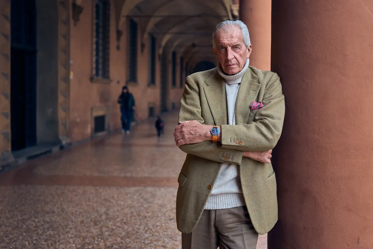 John Goldberger stands there, dressed in a light-coloured, elegant suit, leaning against a pillar