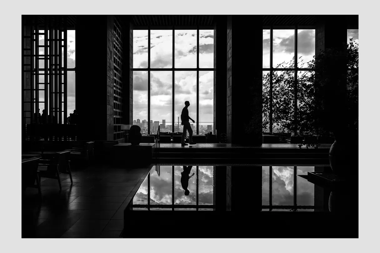 Black and white photography of a man in a house with pool