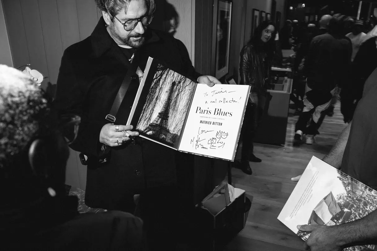 Photographer Mattieu Bitton is holding a book signed by him at a Leica exhibition opening in New York