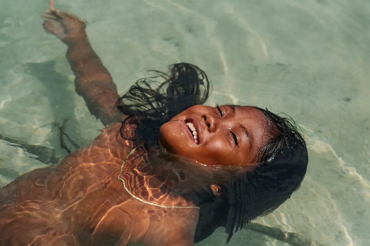 Enfant qui flotte, heureuse, dans l’eau.