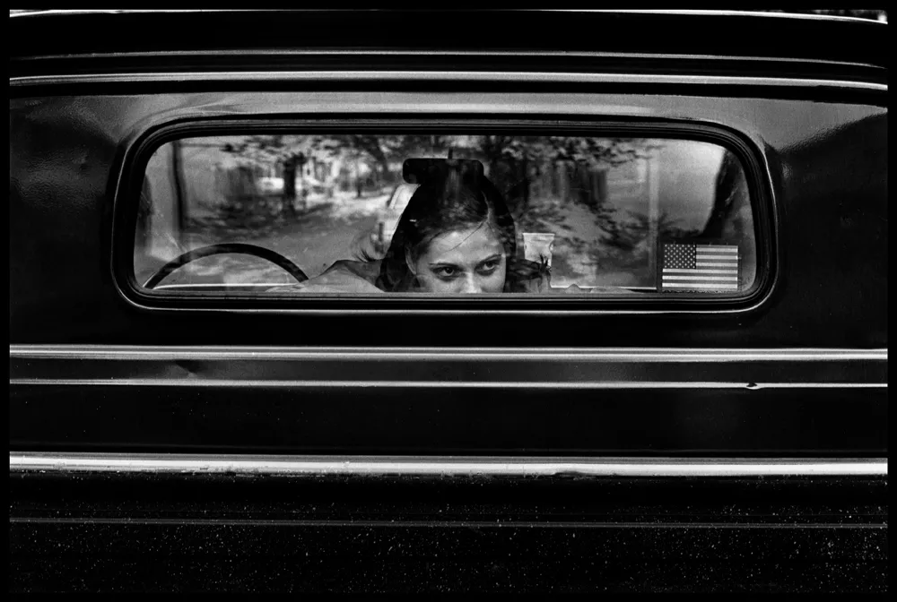 child sitting on the back seat of a car b&w