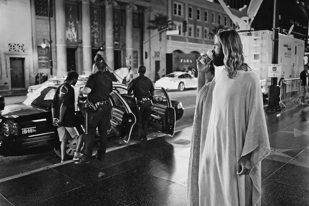man in a jesus cosplay eating icecream b&w