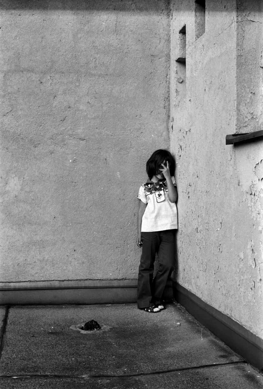 child standing in corner b&w