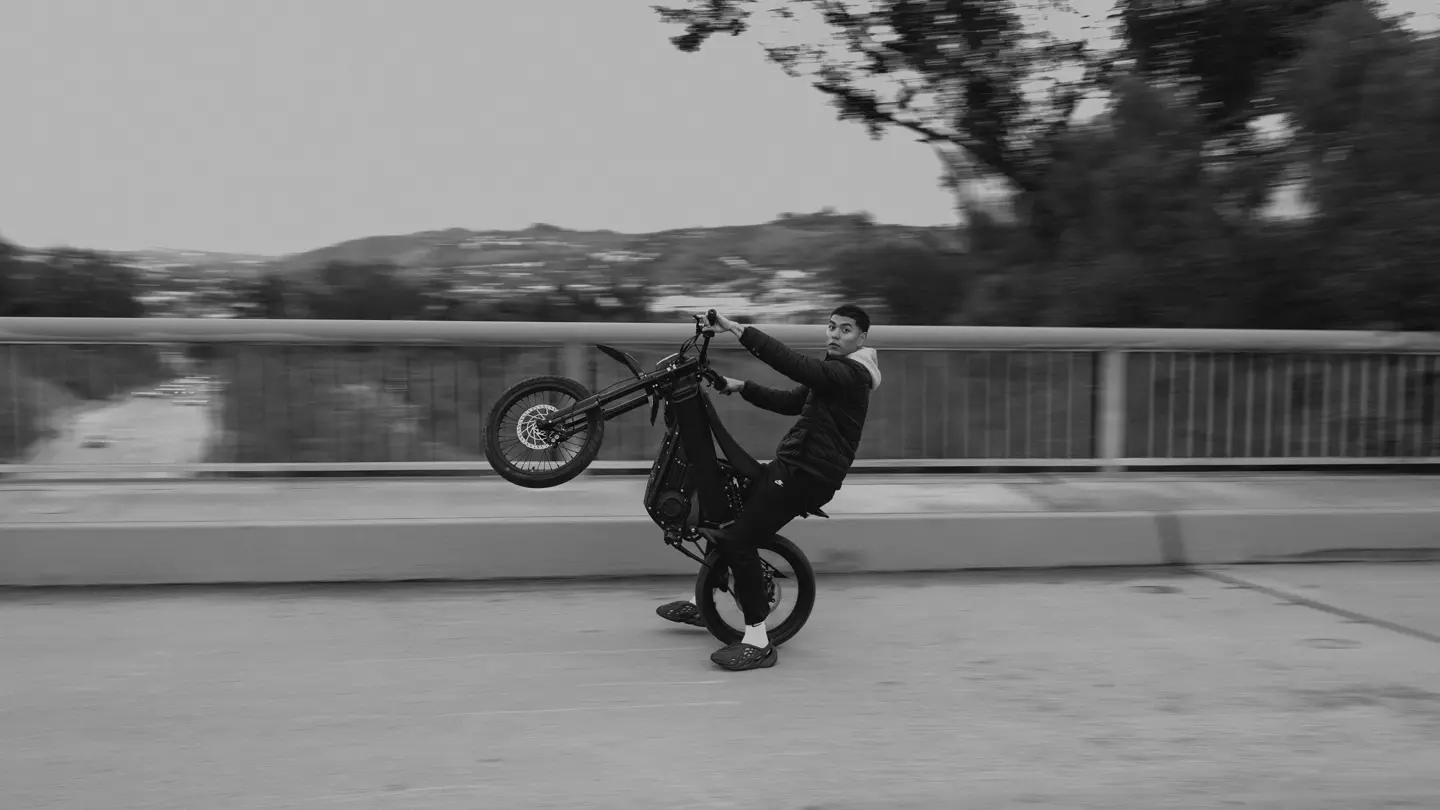 Black and white photograph of a young rider doing a motorbike wheelie