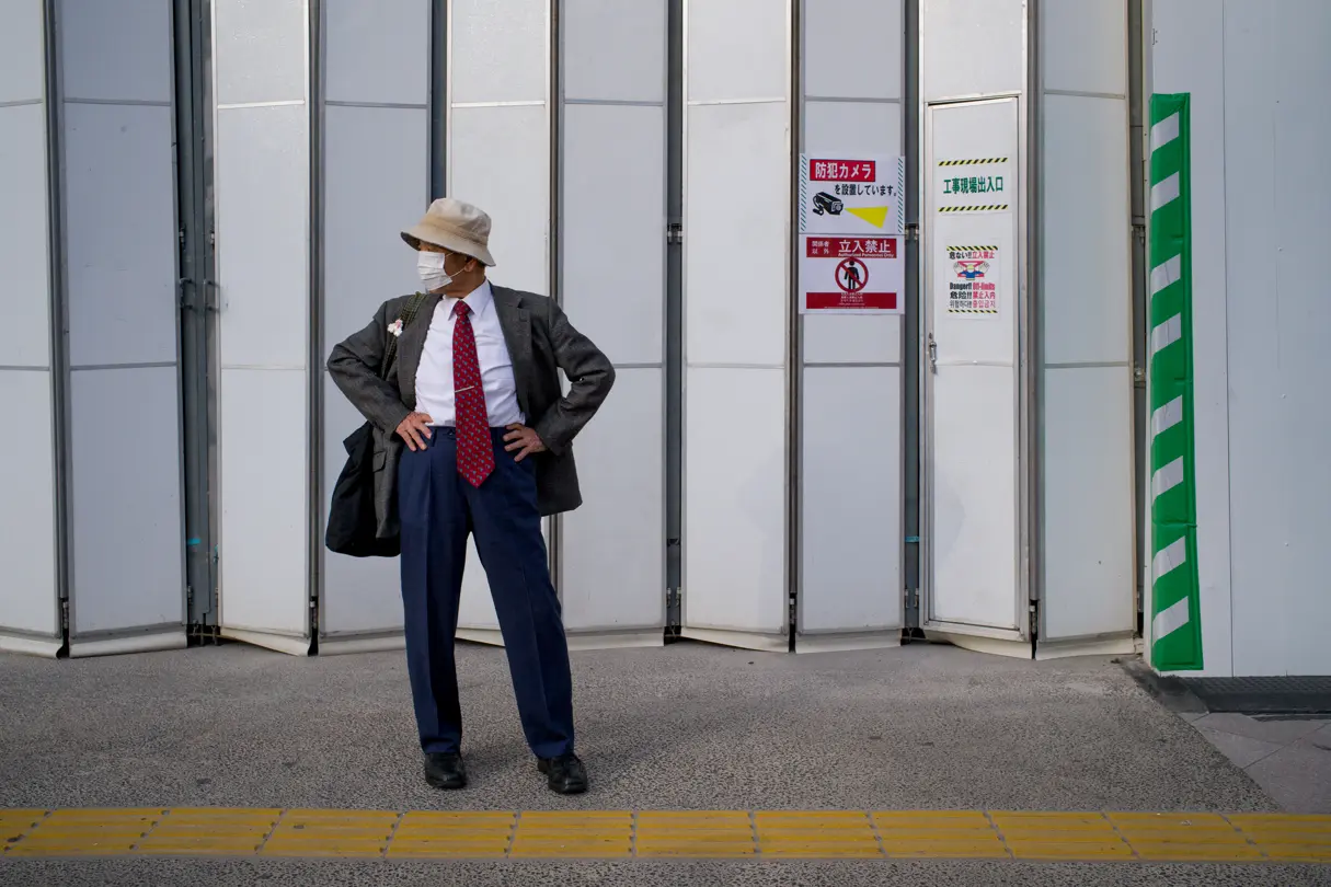 A man wearing a face mask stands by the roadside in Tokyo, waiting