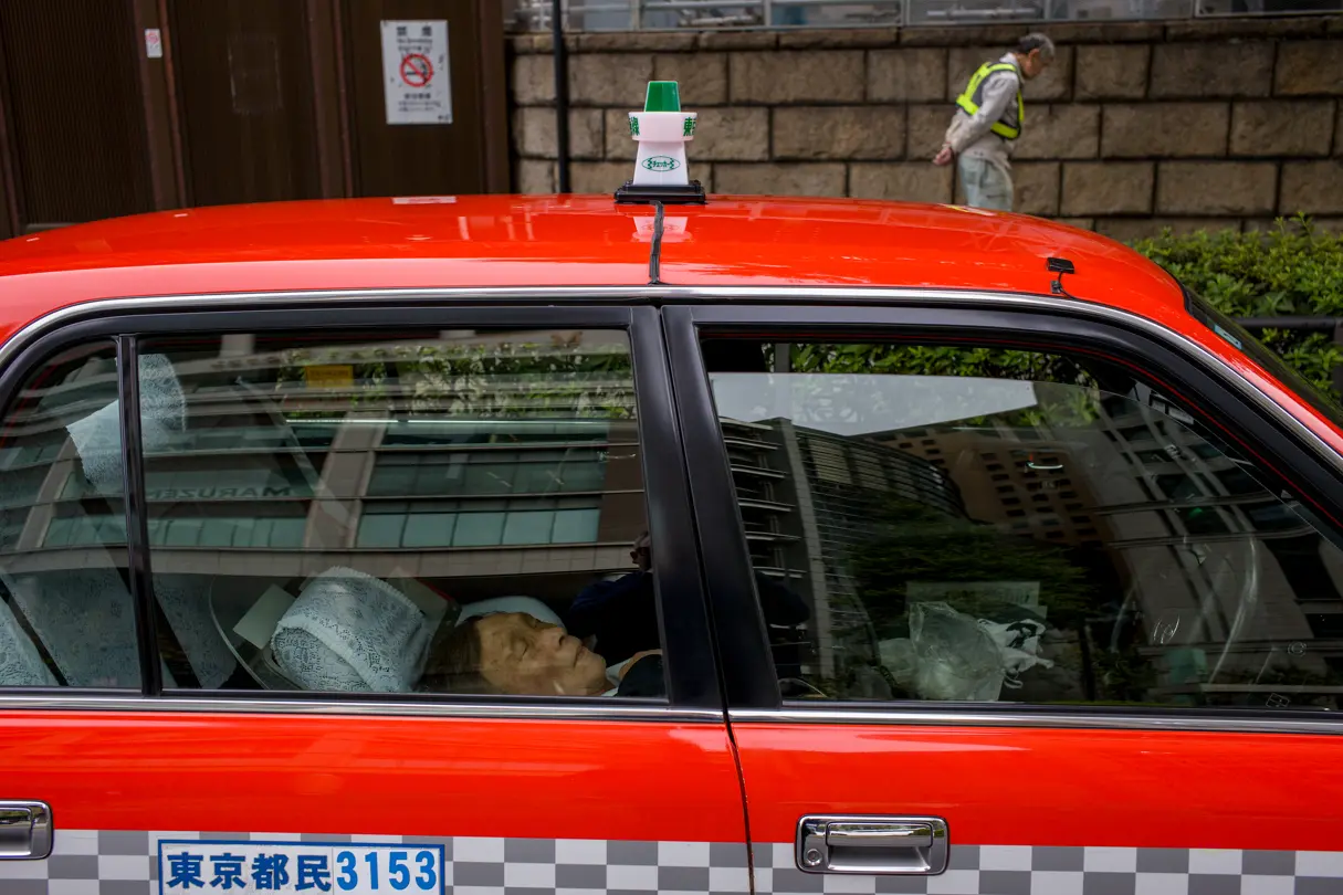 A woman is lying in a red taxi, asleep