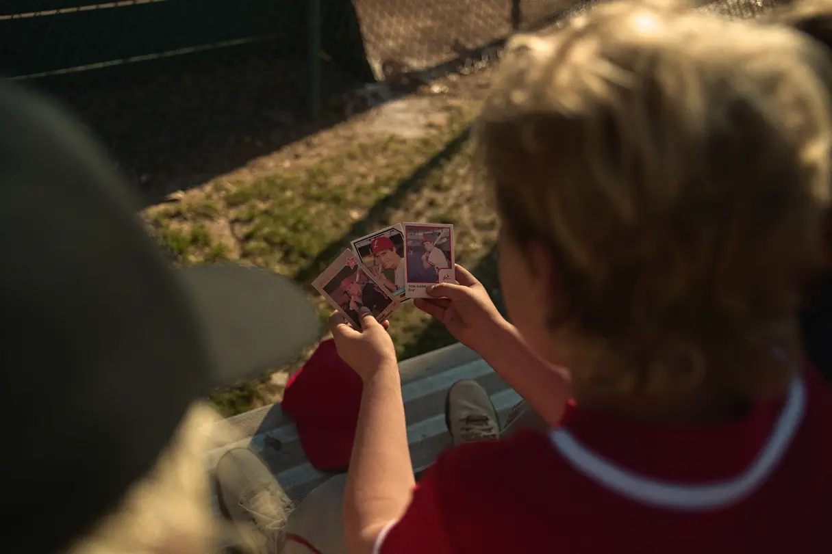 Three boys are looking at baseball cards
