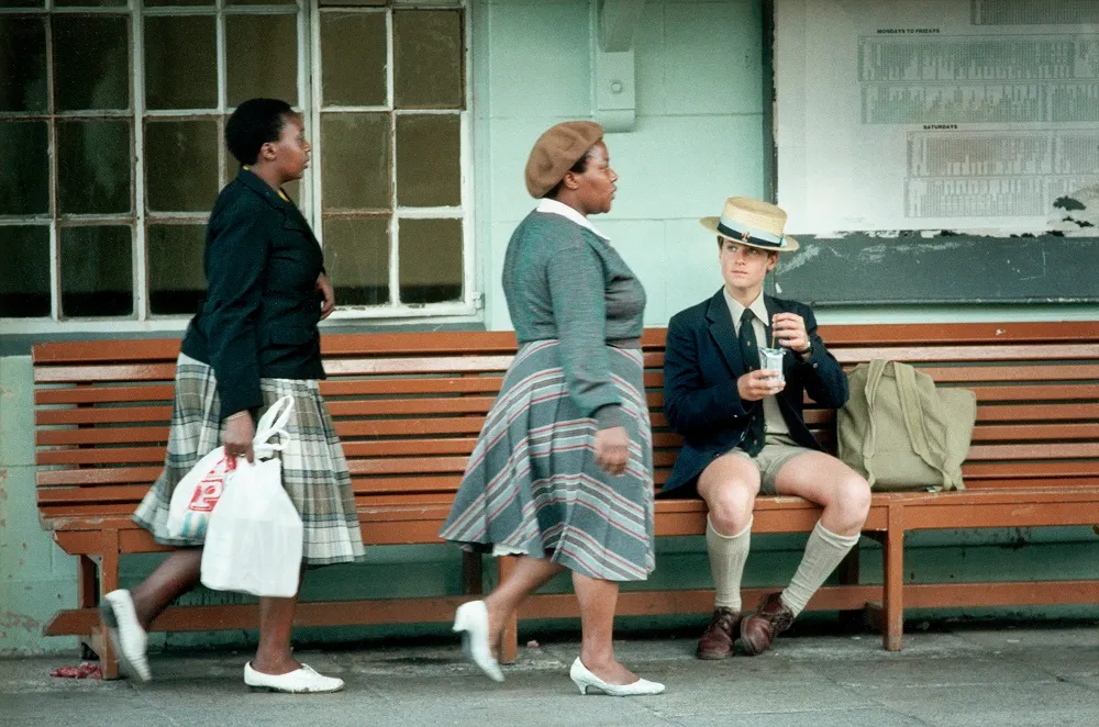two women walking, white man on the bench
