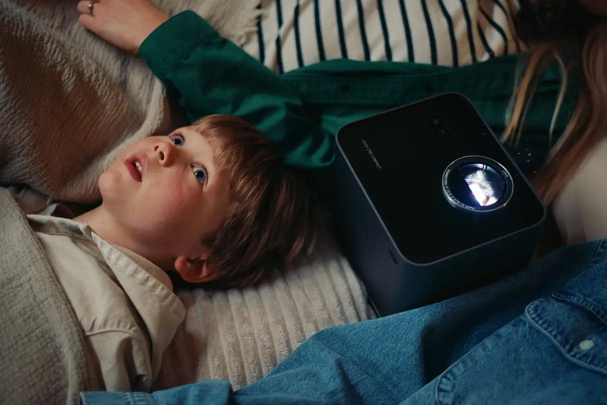 A child lying on the floor looking up at the ceiling; Leica projector in the middle