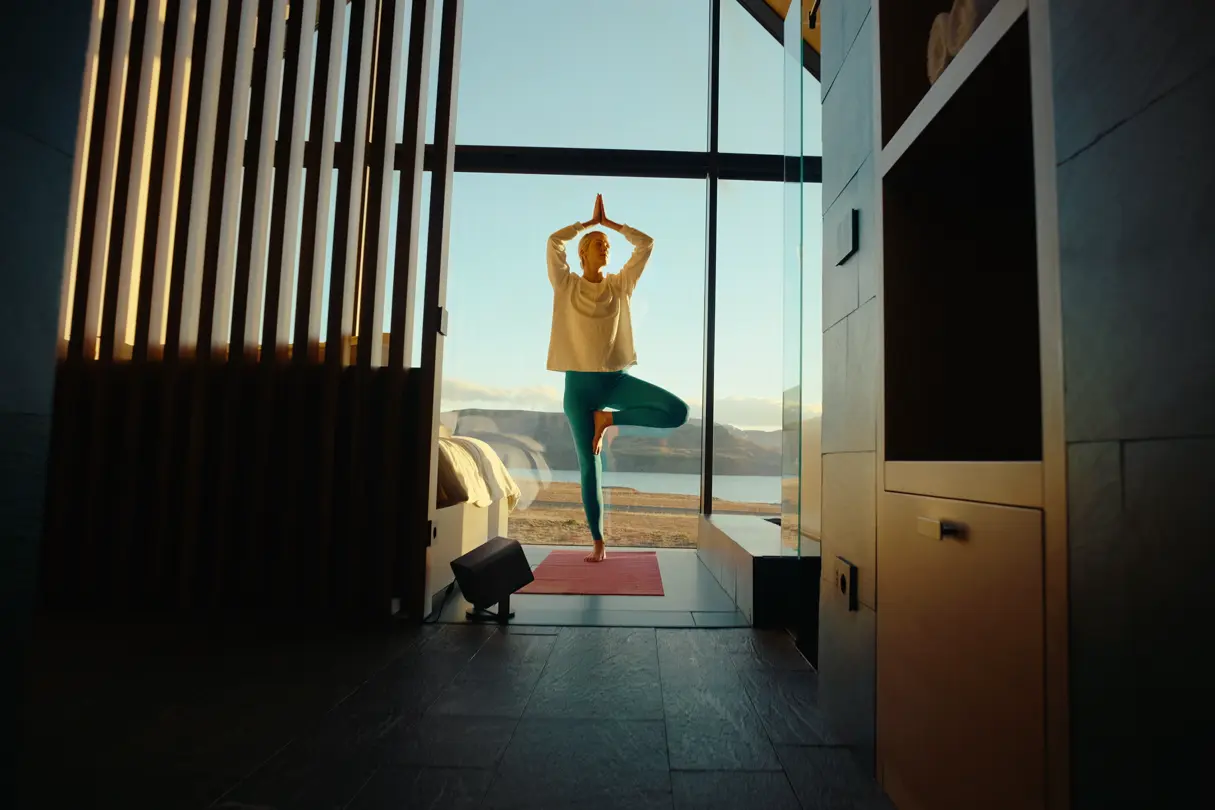 A woman is doing yoga in front of a large window