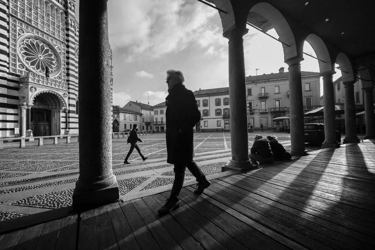 black-and-white photograph, a man walking across a square