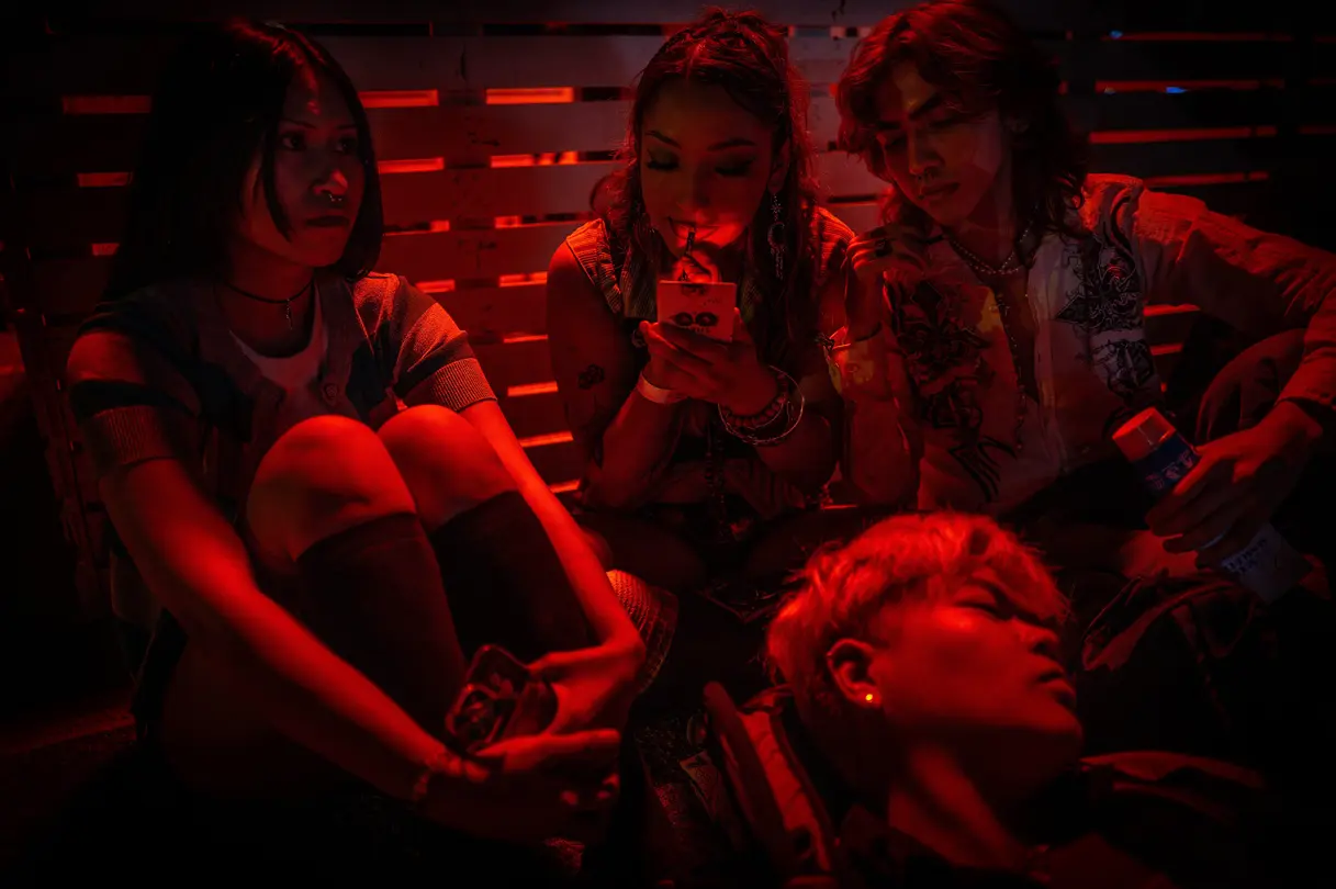 Group of young people gathered under red neon lighting, capturing contemporary nightlife and youth culture.