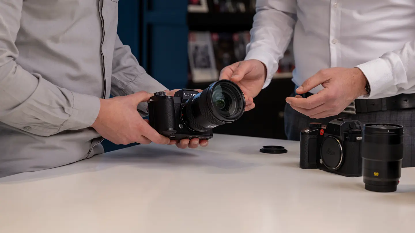 Customer exploring Leica Trade-In options while testing a Leica SL-System camera with a Leica expert.