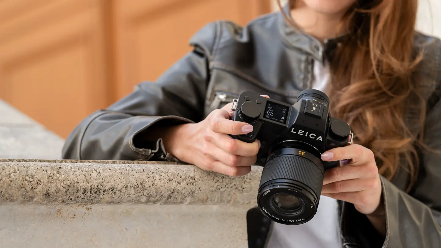 Close-up of a photographer adjusting a Leica camera.