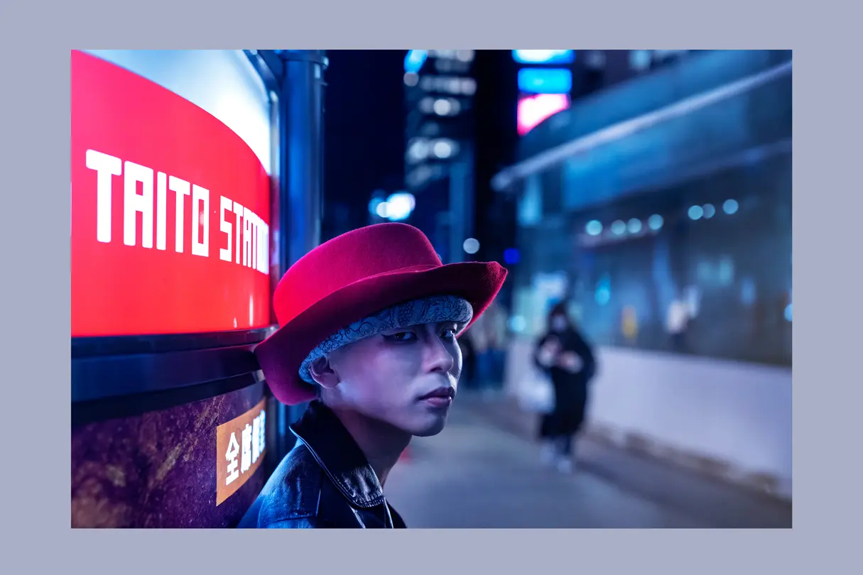 Portrait of a young person beneath neon lights in Tokyo at night. Cinematic urban photography capturing youth culture, color, and atmosphere.