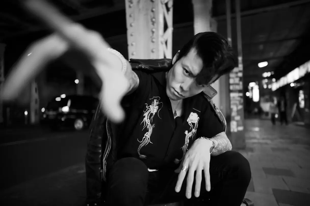 Portrait of a young man in Tokyo nightlife, framed by dramatic perspective and urban surroundings.