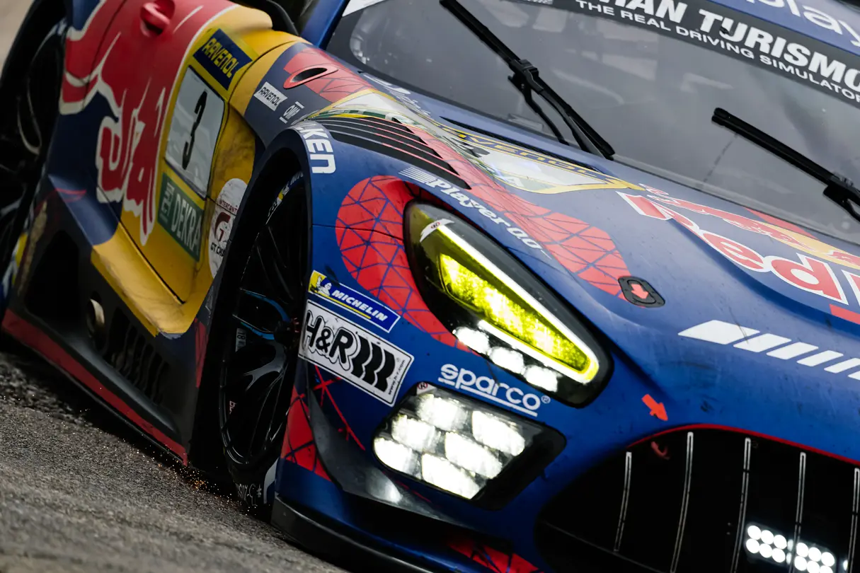 Close-up of a GT race car on a wet circuit, showcasing vibrant motorsport livery and performance details.