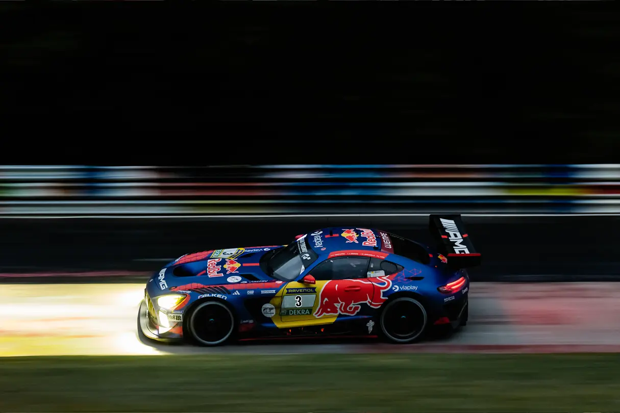 GT race car speeding through a circuit corner, captured with dynamic motion blur and vivid racing colors.