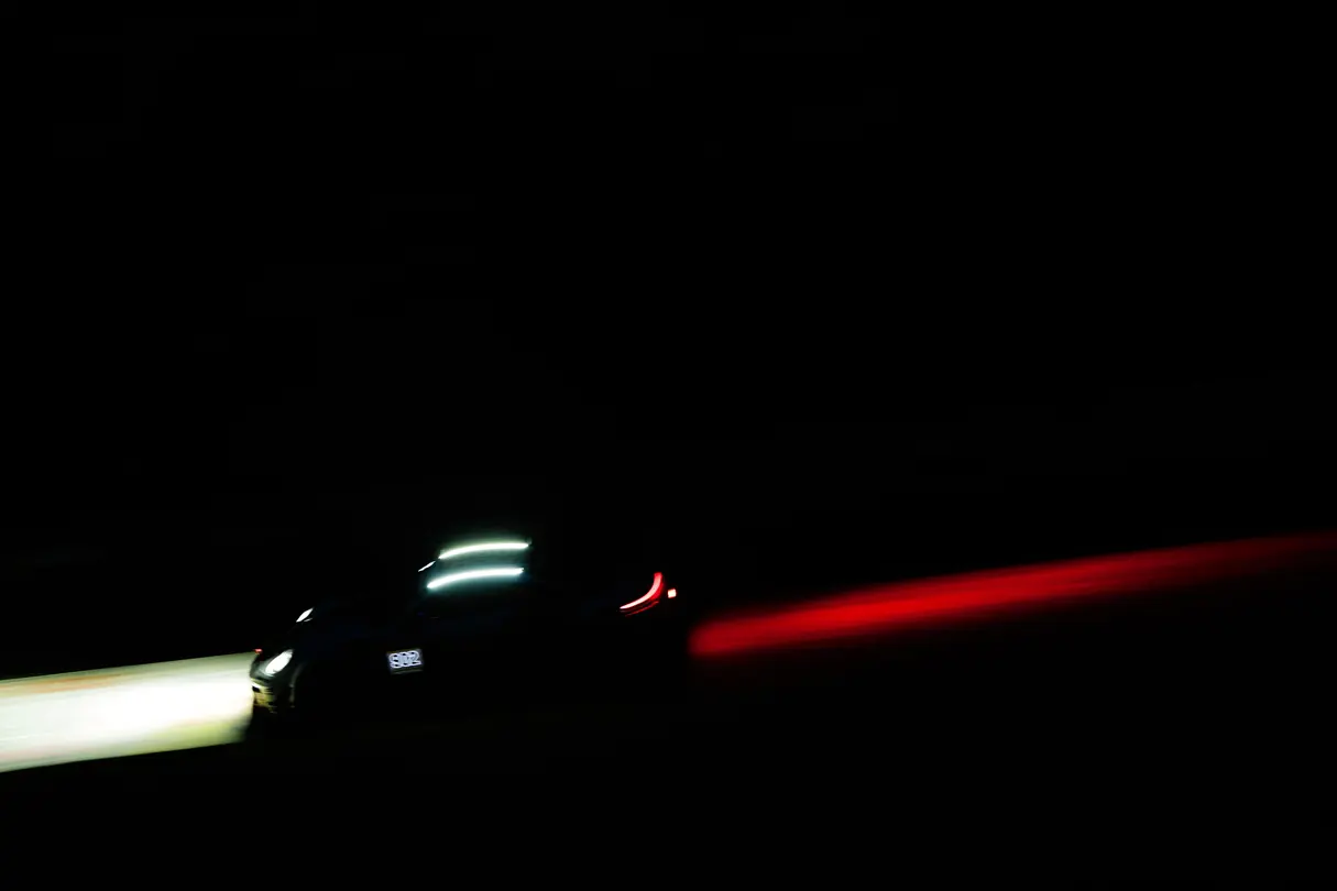 High-performance race car speeding through darkness, defined by striking light trails and motion blur.