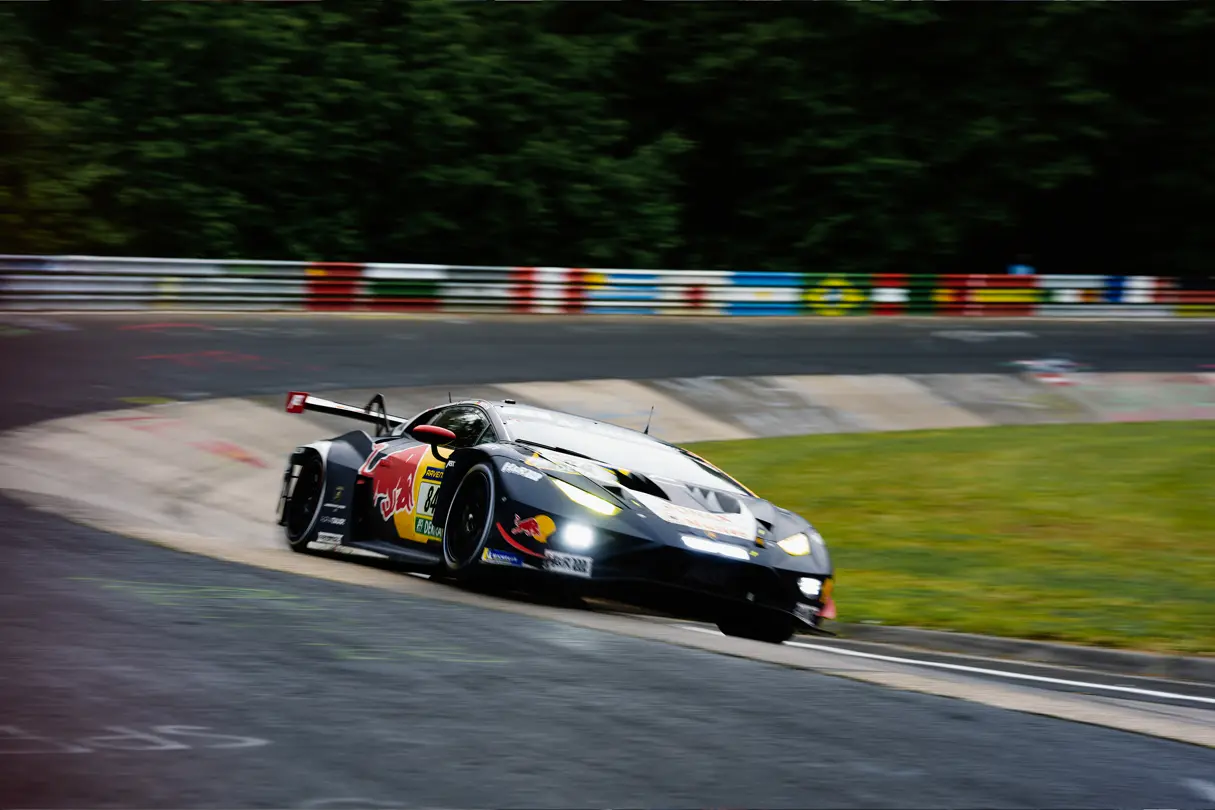 GT race car attacks a circuit corner at speed, showcasing dynamic motorsport action and precision driving on track.