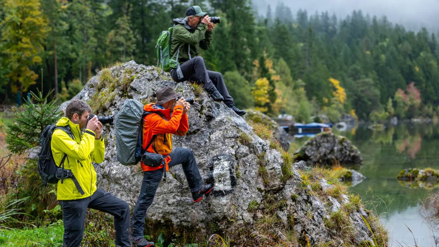 Photographers capturing landscapes beside a mountain lake.