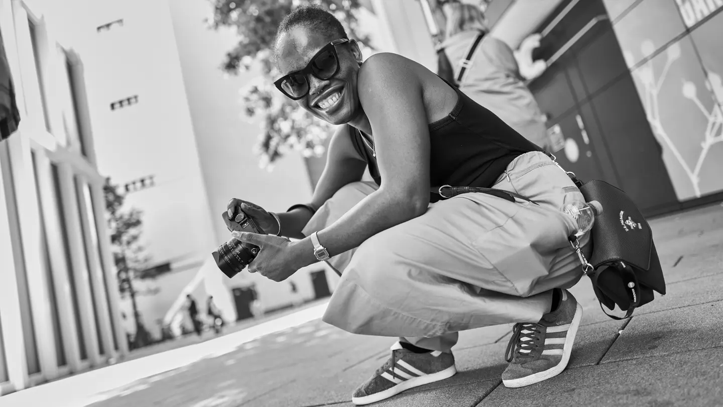 Smiling person holding a Leica camera during a street photography workshop.