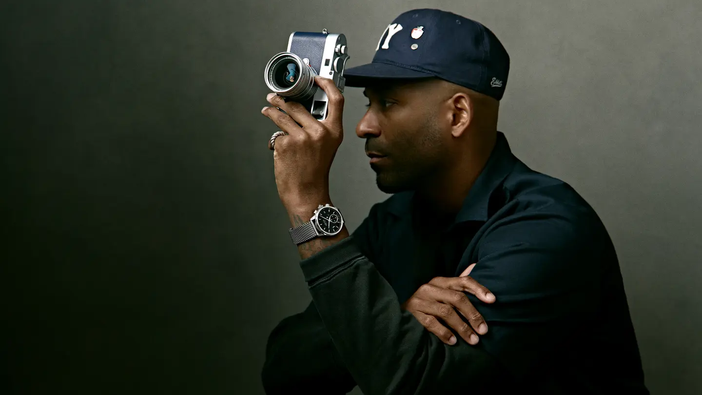 Portrait of Jason Roman holding a Leica rangefinder camera, showcasing creative vision, craftsmanship, and contemporary photography culture.
