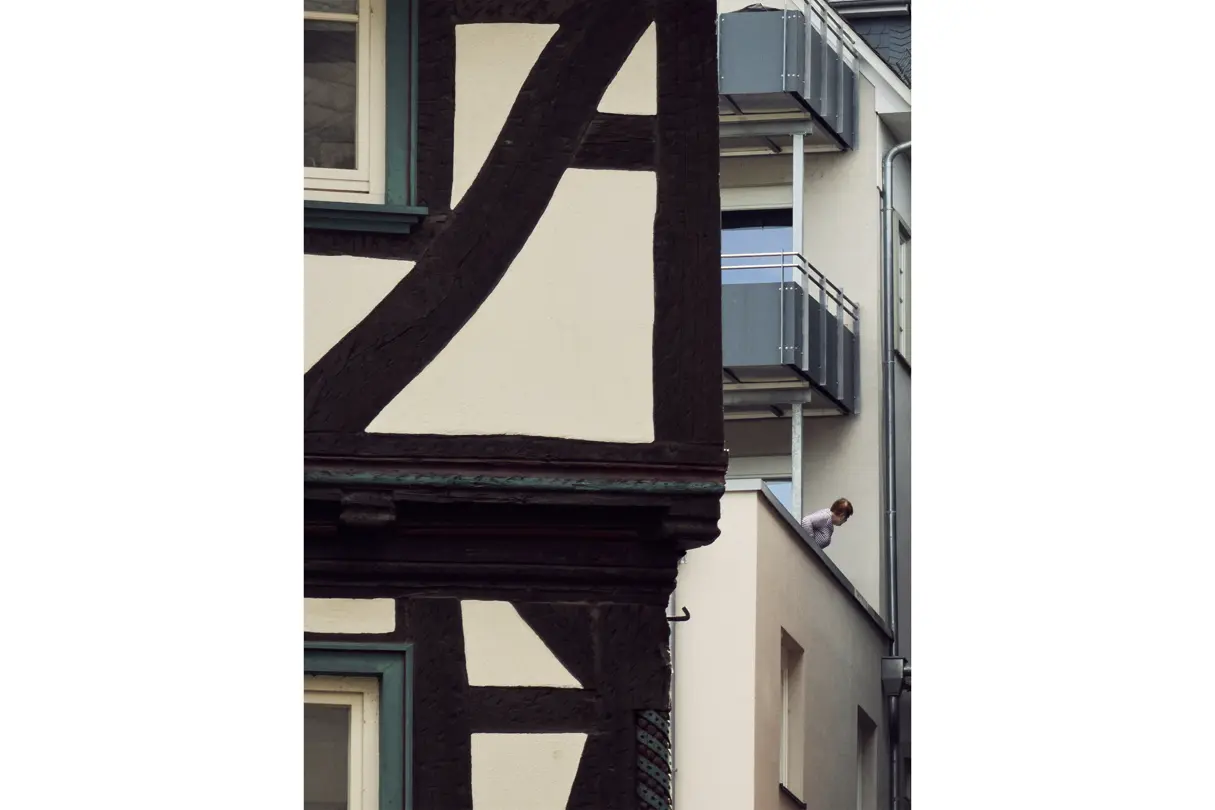Traditional half-timbered architecture contrasted with modern balconies, capturing the blend of old and new city design.