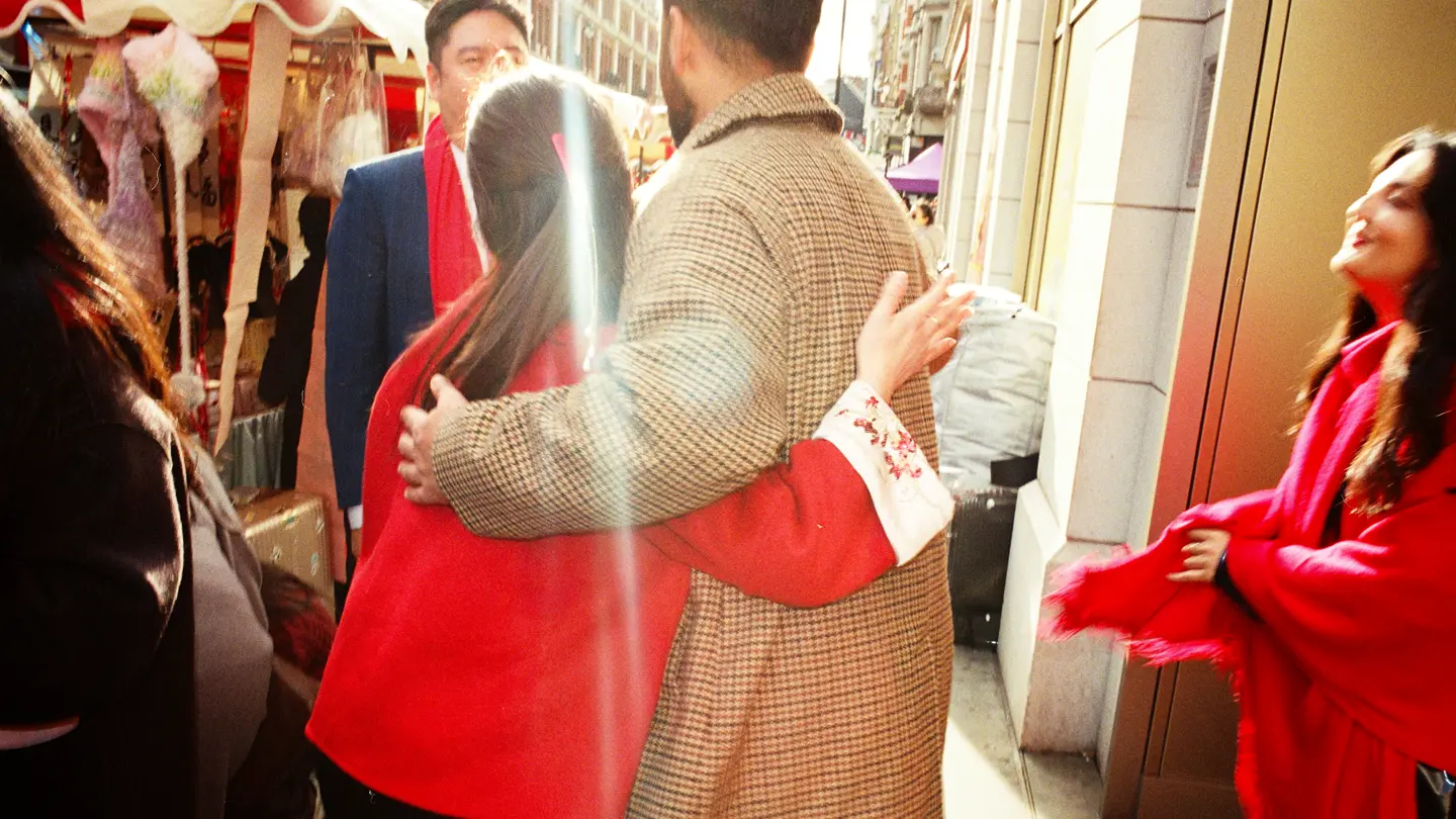 Colour photo of a a couple embracing on the street with flare going across the frame.