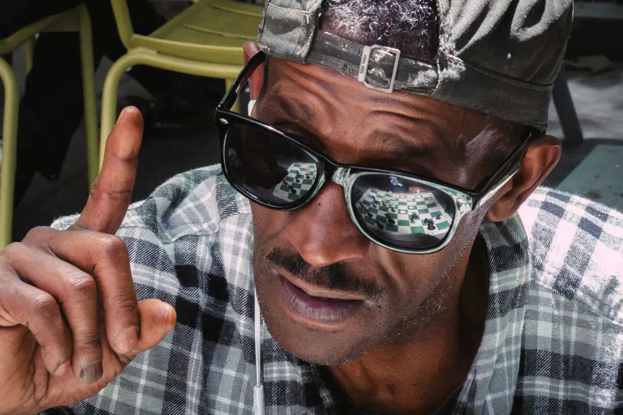 Close-up of a chess player with the game reflected in their sunglasses.