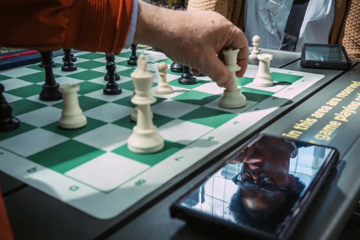 Close-up of a chess player moving a piece during an outdoor game.