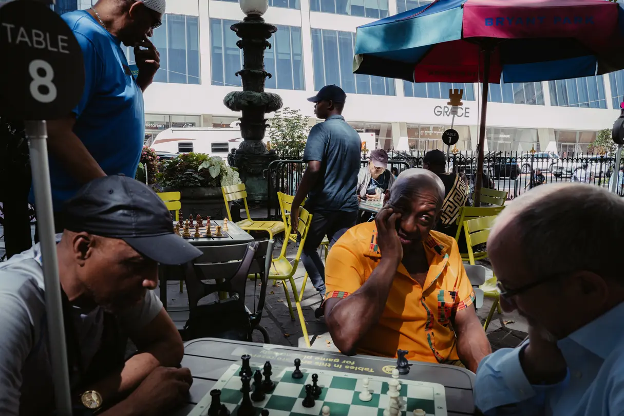 People playing chess at outdoor tables in Bryant Park.