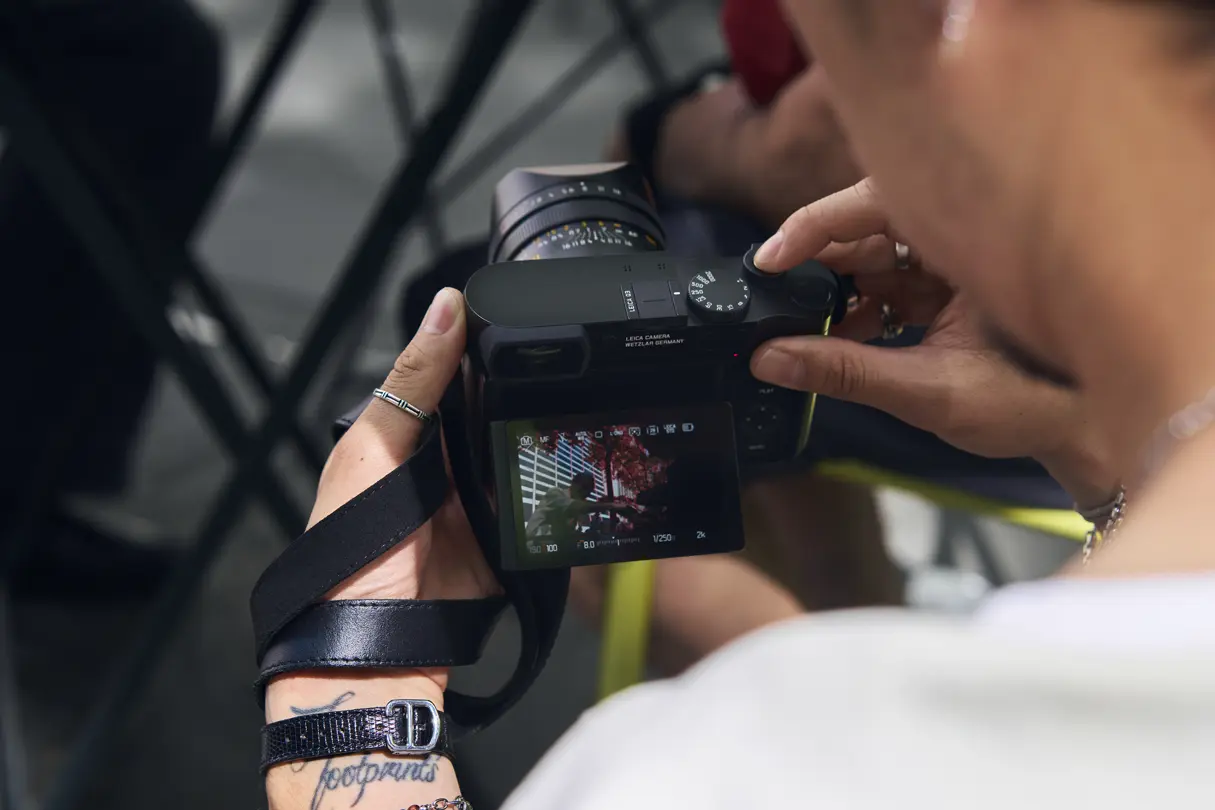 Photographer Billy Dinh reviews images on a Leica Q camera display after capturing candid street photography in a New York City park.