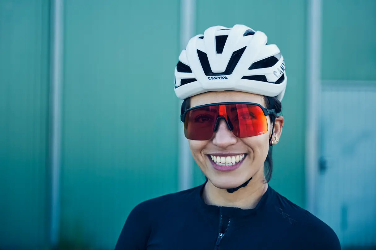 Portrait von Rennradfahrerin mit Brille vor grünem Hintergrund