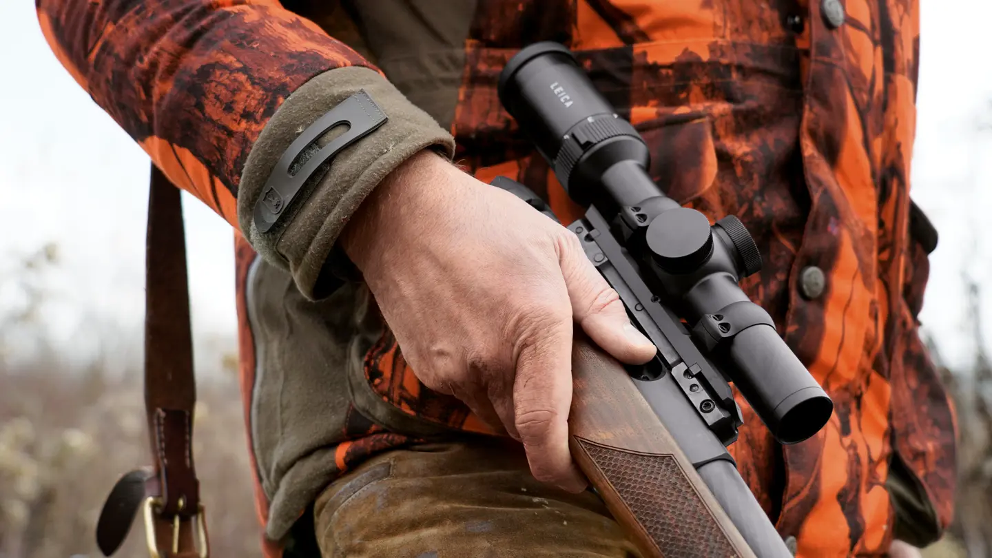 Close-up–of–a–hunter–holding–a–Leica–Fortis–and–wearing–orange–camouflage