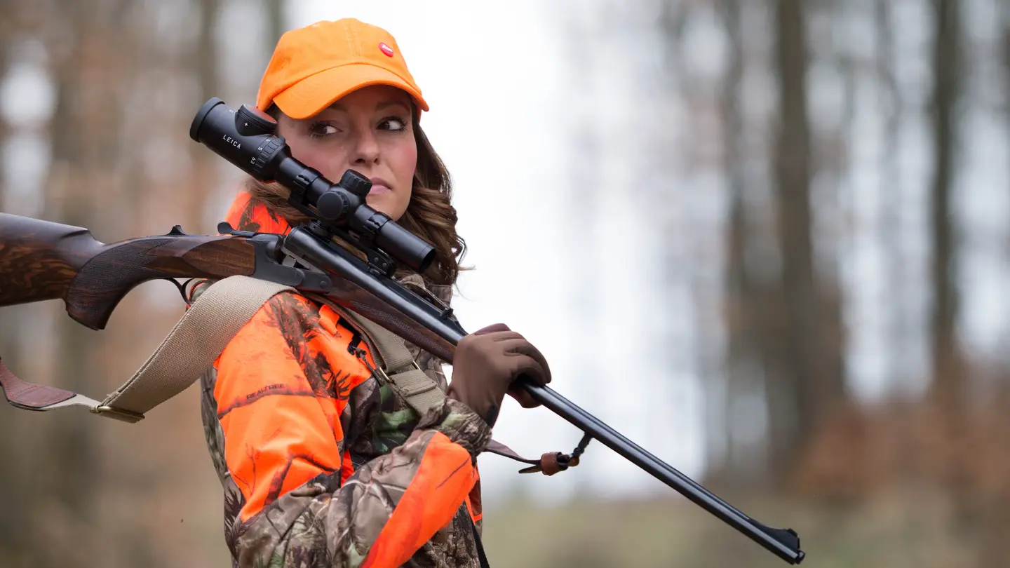 Hunter–carrying–a–rifle–with–a–Leica–Magnus–through–a–forest