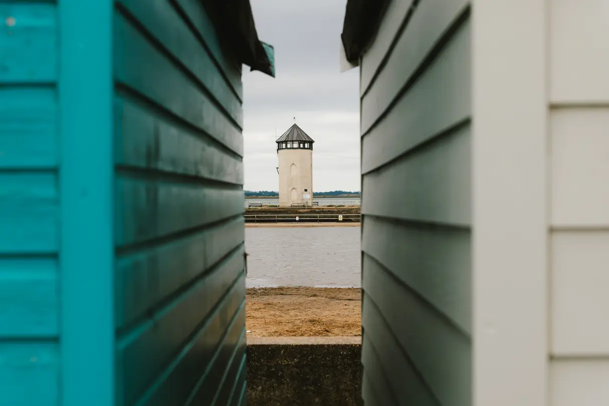 A lighthouse photographed through two beach houses