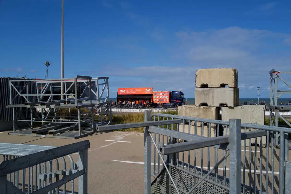 Max Verstappen merchandise stand at the Dutch Grand Prix in Zandvoort, framed by temporary event structures and the North Sea coastline.
