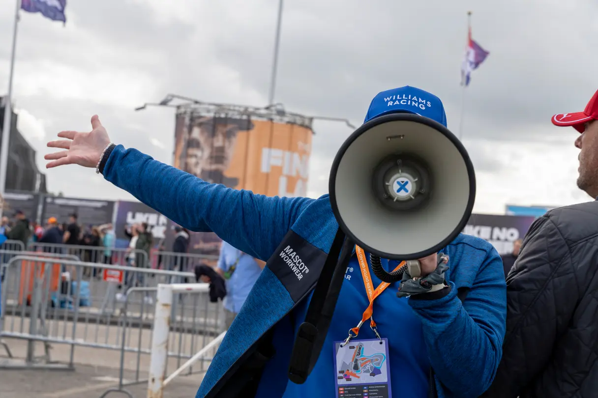 Event staff member wearing a Williams Racing cap speaks through a megaphone at the Dutch Grand Prix in Zandvoort.