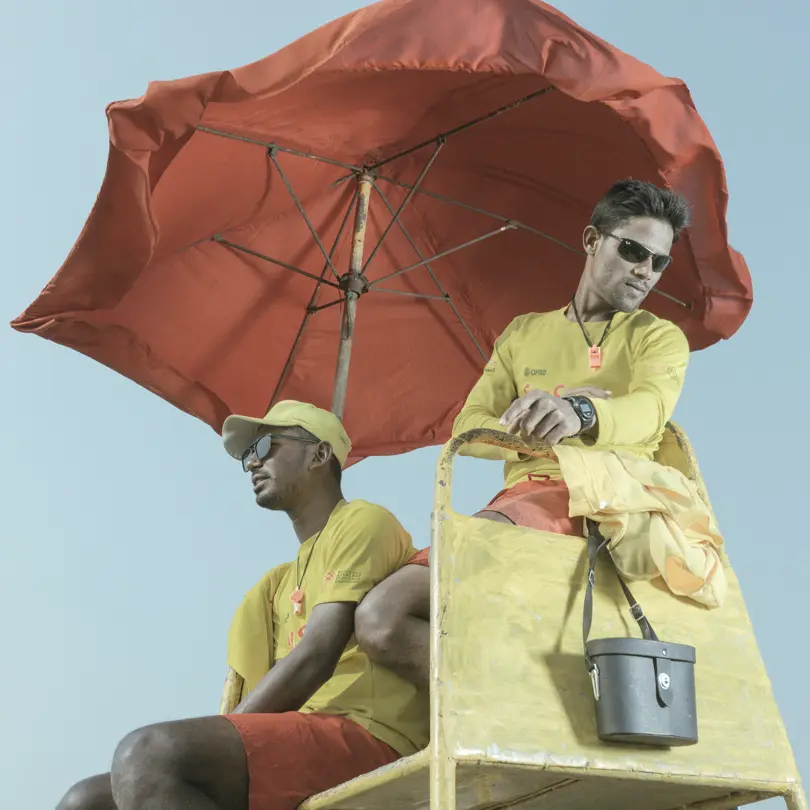 LOBA Winner 2023 image: 2 lifeguards in yellow clothes on a yellow chair with a red sunshade